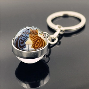 Macro shot of glass dome keychain featuring two cats illustration on black reflective base