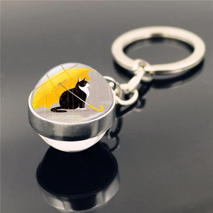 Round glass keychain featuring a black cat under a yellow umbrella with silver ring