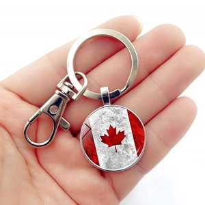 Vintage Canada flag keychain with maple leaf pendant and lobster clasp held in hand