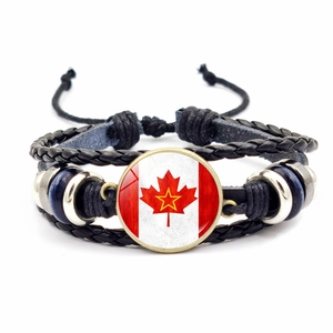Detail of multi-layer braided leather bracelet featuring Canada flag maple leaf glass charm
