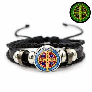 Detailed shot of Saint Benedict medal on a braided leather bracelet with blue enamel