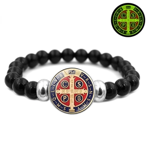 Detail of Saint Benedict medal on black beaded bracelet with red blue enamel and luminous effect