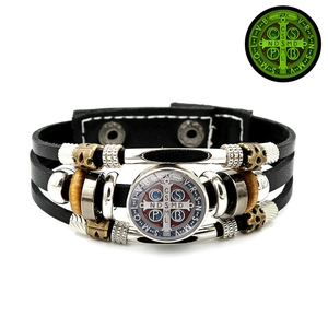 Close-up of luminous St. Benedict medal on multilayer leather bracelet with wooden beads