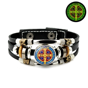 Detailed view of Saint Benedict Medal on multilayer black leather punk braided bracelet