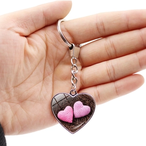 Close-up of handmade heart keychain with pink knitted hearts in resin casing