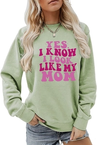Detail of a light green crewneck sweatshirt with pink 'YES I KNOW I LOOK LIKE MY MOM' text