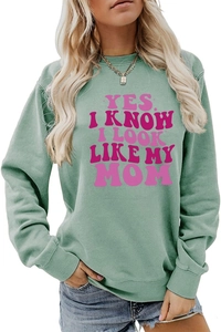 Sage green sweatshirt detail with pink 'YES I KNOW I LOOK LIKE MY MOM' wavy slogan text