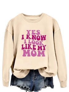 Detail of trendy beige sweatshirt featuring pink YES I KNOW I LOOK LIKE MY MOM lettering