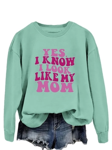 Close-up of mint green sweatshirt with Yes I Know I Look Like My Mom pink slogan