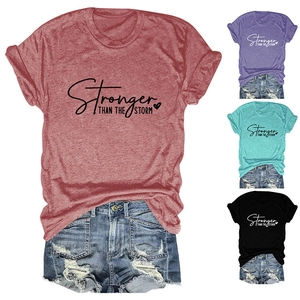 Flat lay of Stronger Than The Storm t-shirts in brick red, purple, mint, and black colors