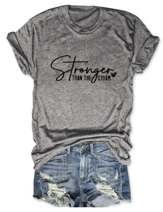 Detail of grey Stronger Than The Storm t-shirt paired with distressed denim shorts