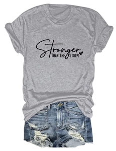 Flat lay of gray Stronger Than The Storm t-shirt with ripped blue denim shorts set