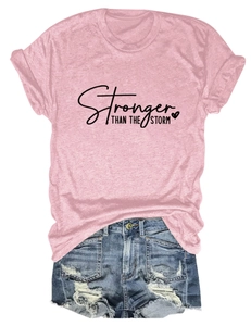 Detail of pink t-shirt with Stronger Than The Storm text and distressed denim shorts