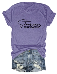 Flat lay of purple heather tee with Stronger Than The Storm text and ripped denim shorts