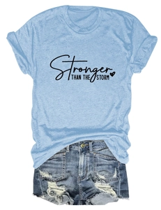 Close-up of Stronger Than The Storm slogan print on a light blue cotton T-shirt