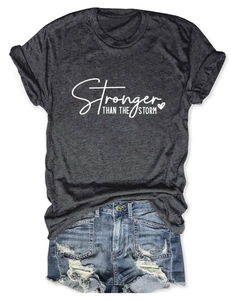 Flat lay of gray Stronger Than The Storm t-shirt paired with distressed denim shorts