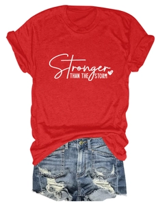 Flat lay of a red cotton T-shirt with Stronger Than The Storm text and denim shorts