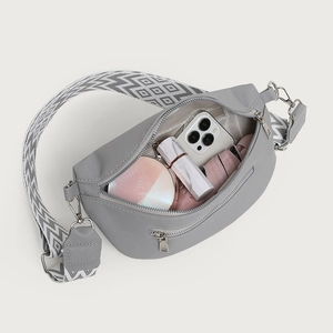 Grey lychee leather crescent crossbody bag with wide geometric strap and interior essentials