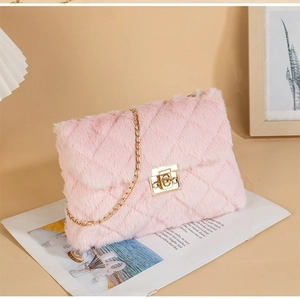 Detailed close-up of pink faux fur crossbody bag with gold chain and metal lock on a magazine