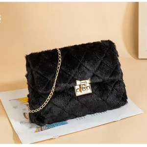Detail of plush black quilted shoulder bag with gold chain and metal twist lock