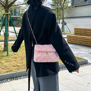 Pink plush crossbody bag with chain strap and quilted faux fur texture shown on model