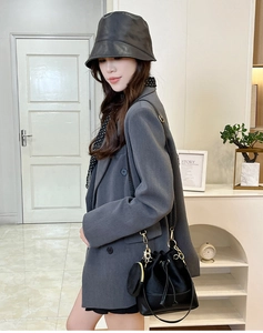 Chic black leather drawstring bucket bag with gold chain detail styled on model