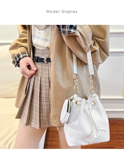 Detail of white PU leather bucket bag with drawstring closure and mini coin purse charm