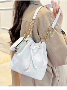 Detail of white drawstring bucket bag with chain strap and matching coin purse on a model