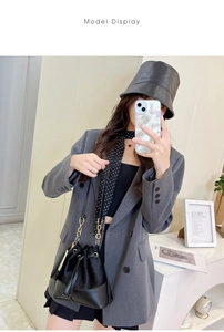 Detail of black drawstring bucket bag with gold chain strap and mixed material finish