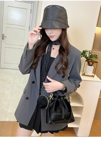 Detail of black drawstring bucket bag set with gold hardware and small round coin purse charm