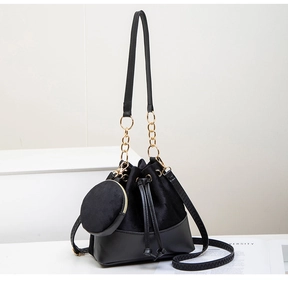 Detail of black drawstring bucket bag with round coin purse and golden metal hardware