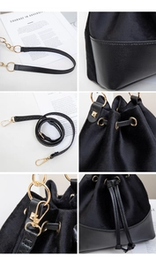 Detail view of black suede bucket bag featuring drawstring closure and gold hardware