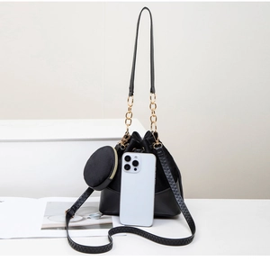 Detail of black drawstring bucket bag with gold chain and matching coin purse accessory