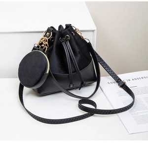 Detail view of black velvet bucket bag with smooth leather finish and gold chain strap
