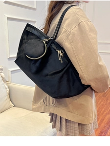 Detail of black suede tote bag showing large capacity texture and gold swan charm
