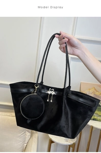 Close-up of black velvet tote bag with swan pendant and small round zipper pouch
