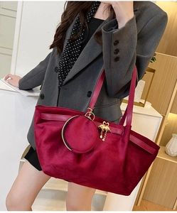Detail of burgundy velvet tote bag featuring a gold swan charm and matching coin purse