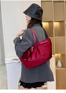 Detail of burgundy suede tote bag featuring a heart-shaped charm and slim shoulder strap