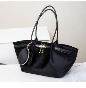 Detail of black velvet tote bag with golden swan heart clasp and hanging round coin purse