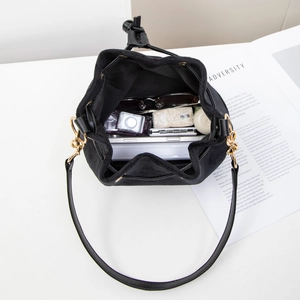 Minimalist black faux suede bucket bag shown with daily essentials in spacious interior