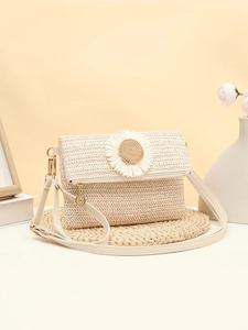 Detail of straw woven crossbody bag featuring a large daisy floral applique and gold zipper