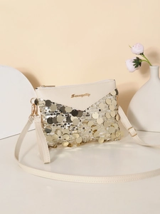 Close-up of beige sequin crossbody bag featuring gold metal logo and V-shaped flap