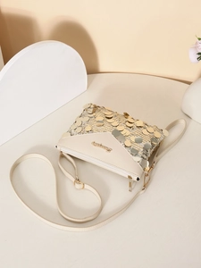Detailed close-up of ivory sequin crossbody bag with gold accents on a white table