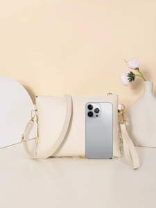 Close-up of cream PU crossbody bag next to a smartphone for size comparison