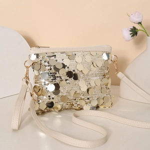 Macro dettagliata di grandi paillettes dorate su borsa a tracolla bianco avorio con dettagli oro
