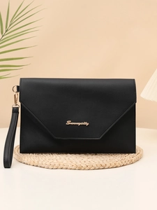 Detail of black envelope clutch bag featuring gold logo and leather wrist strap