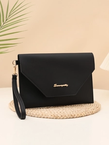 Detail of black envelope clutch featuring a triangular flap and golden metal logo