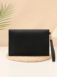 Detail of black matte leather clutch featuring gold hardware and detachable wrist strap