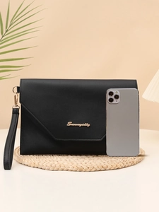 Close-up of black envelope clutch with gold metal logo and detachable wrist strap