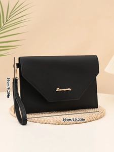 Detail view of a black envelope clutch with gold logo, measuring 26cm by 16cm in size